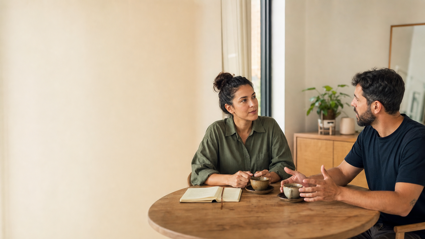 Dois adultos conversam com atenção e respeito em uma mesa, em ambiente acolhedor.
